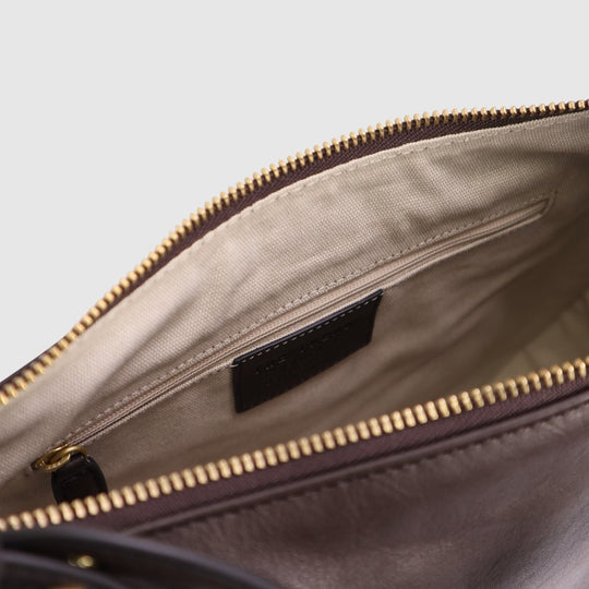 Hobo bag interior close-up showing beige lining, black pocket, and gold zipper edge.