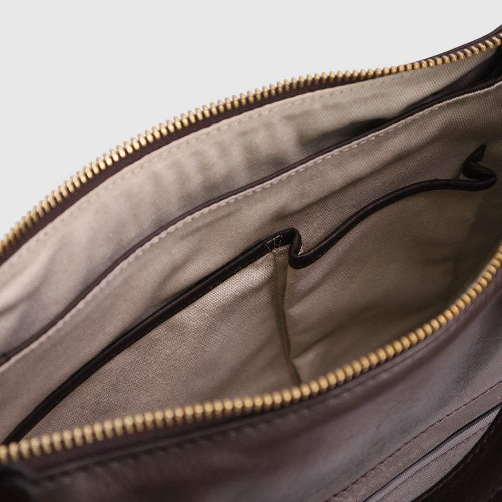 Hobo bag interior view with beige lining, black inner pocket, and gold zipper trim.