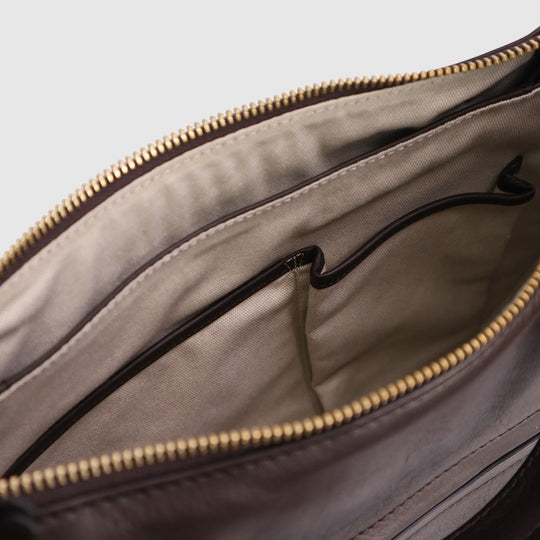Hobo bag interior view with beige lining, black inner pocket, and gold zipper trim.