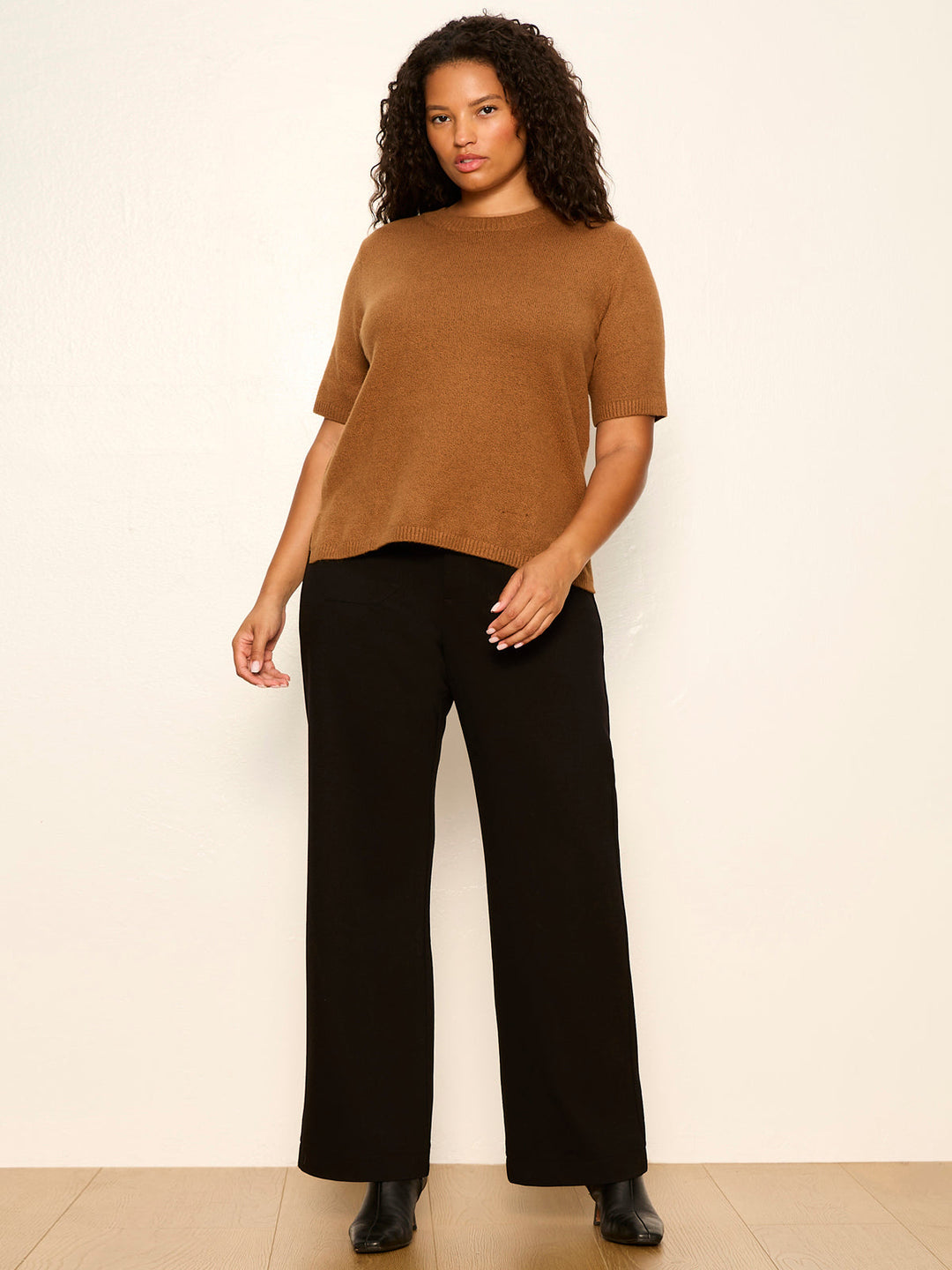 Brown short-sleeve knit tee with ribbed crew neck, worn with black pants