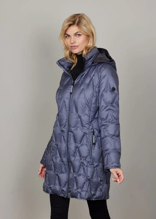 Woman wearing a blue quilted coat against a plain background
