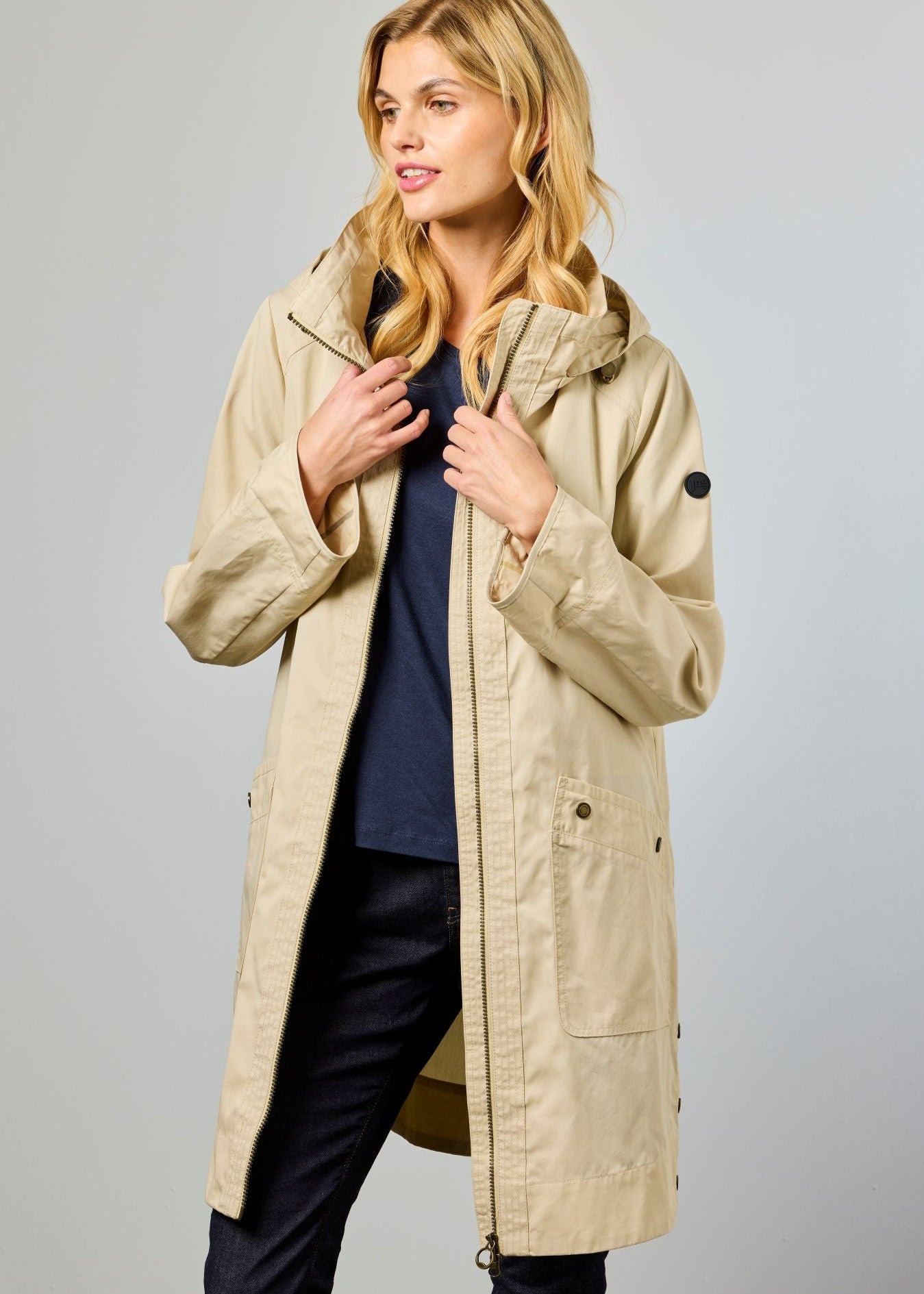 Woman wearing a beige coat against a gray background