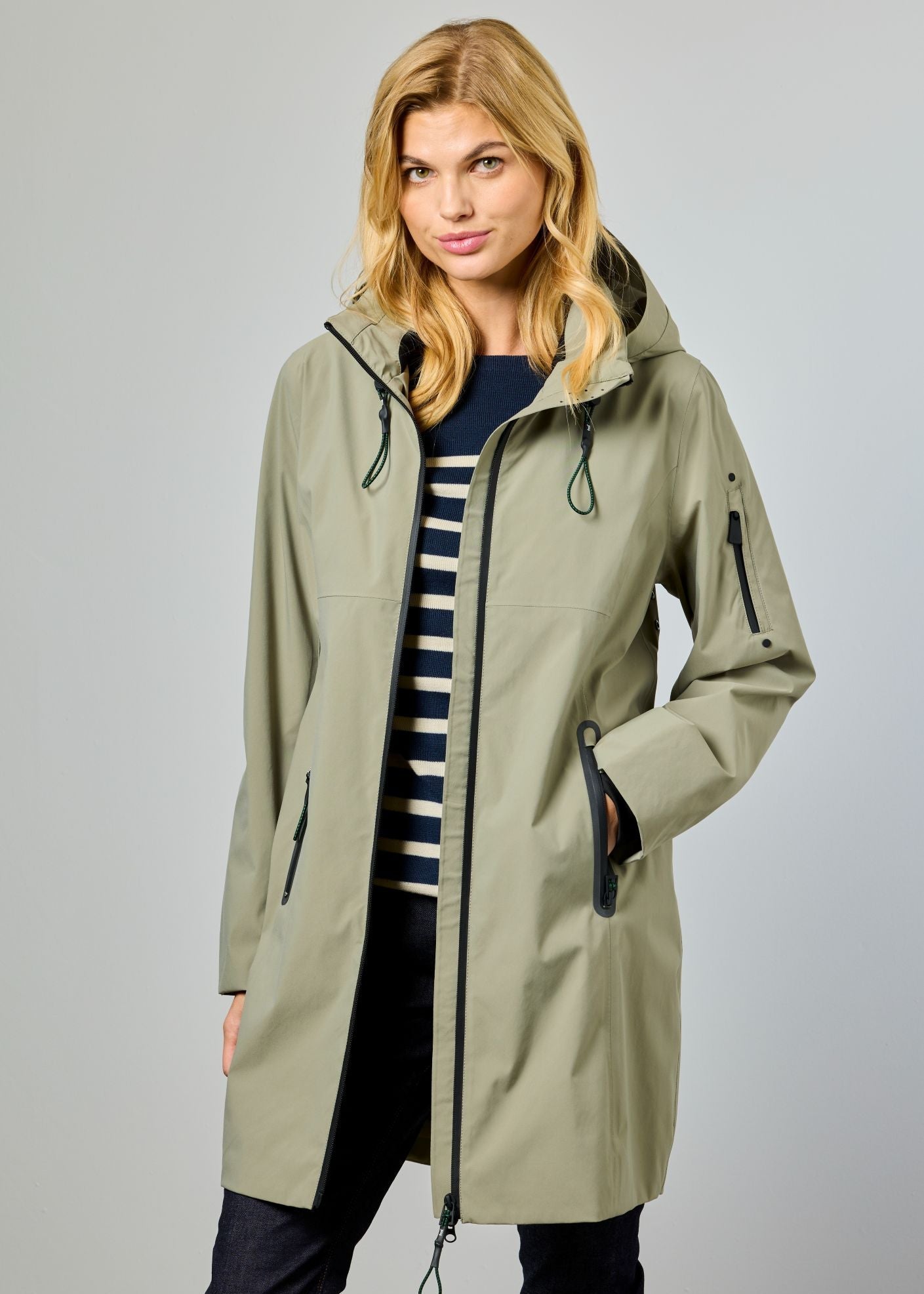Woman wearing a long beige raincoat on a gray background