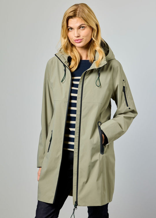 Woman wearing a long beige raincoat on a gray background