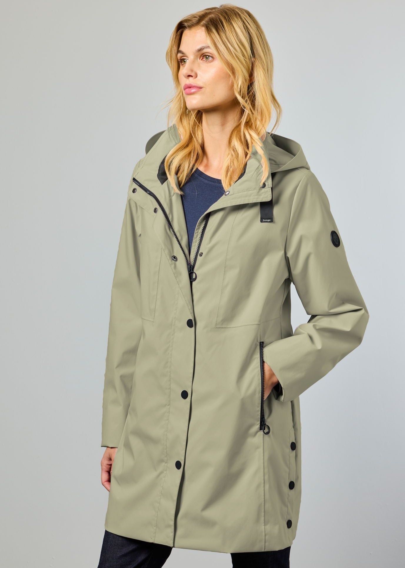 Woman wearing a green raincoat against a gray background