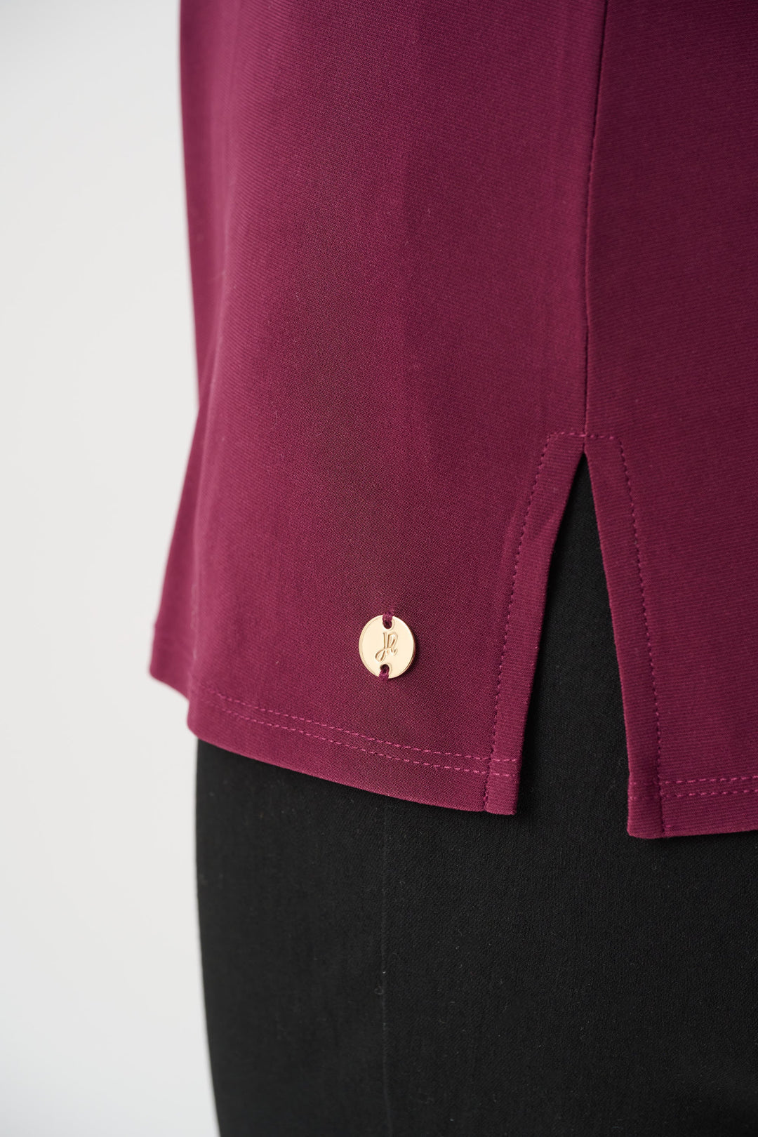 Wine-purple cami hem detail with gold button and side slit.