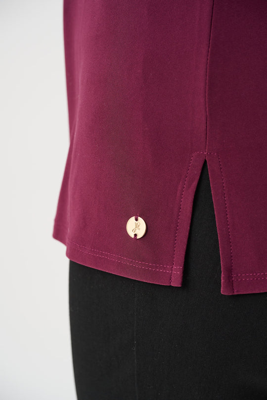 Wine-purple cami hem detail with gold button and side slit.