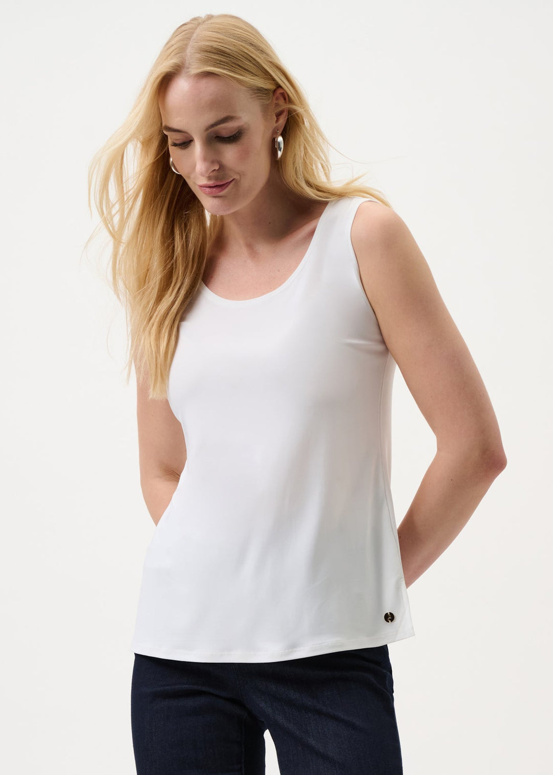 Woman wearing a white sleeveless top and navy pants on a white background