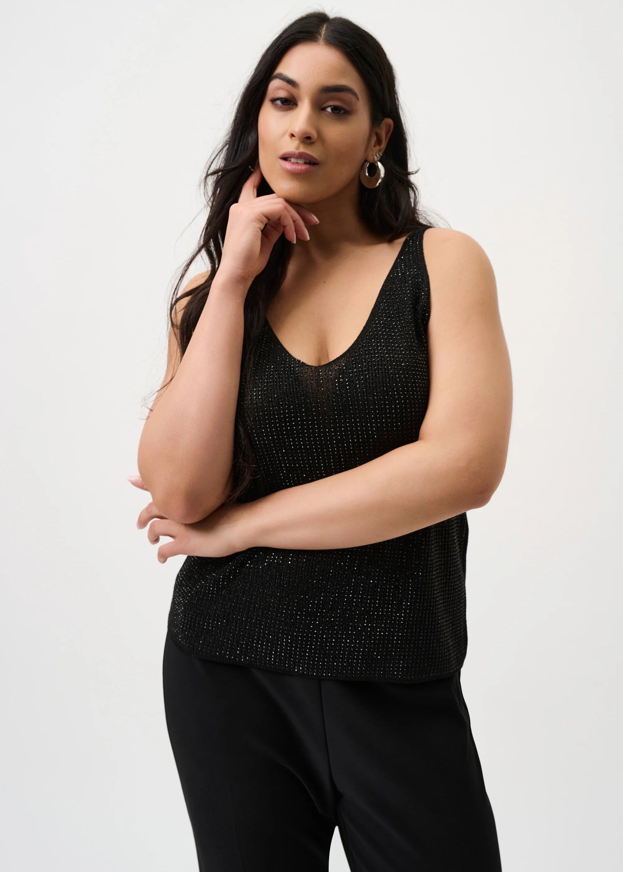 Woman wearing a black sleeveless top with a textured pattern on a white background