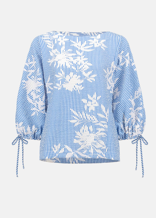 Blue and white floral blouse with tie sleeves on a light gray background