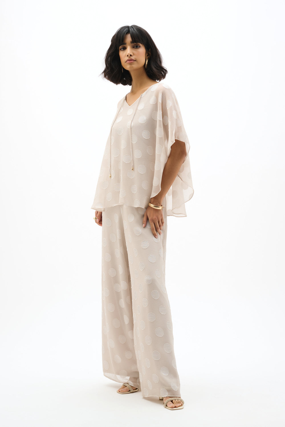 Light colored chiffon poncho top with polka dot pattern worn by model