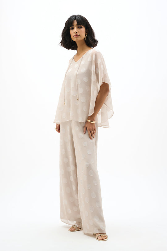 Light colored chiffon poncho top with polka dot pattern worn by model