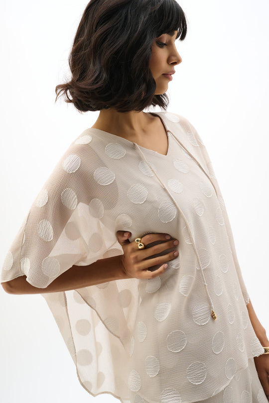 Light colored chiffon poncho top with polka dot pattern, three-quarter sleeves, side view