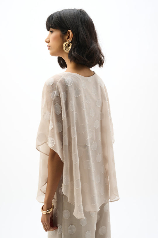 Flowing chiffon poncho top with polka dot pattern, side profile view on model