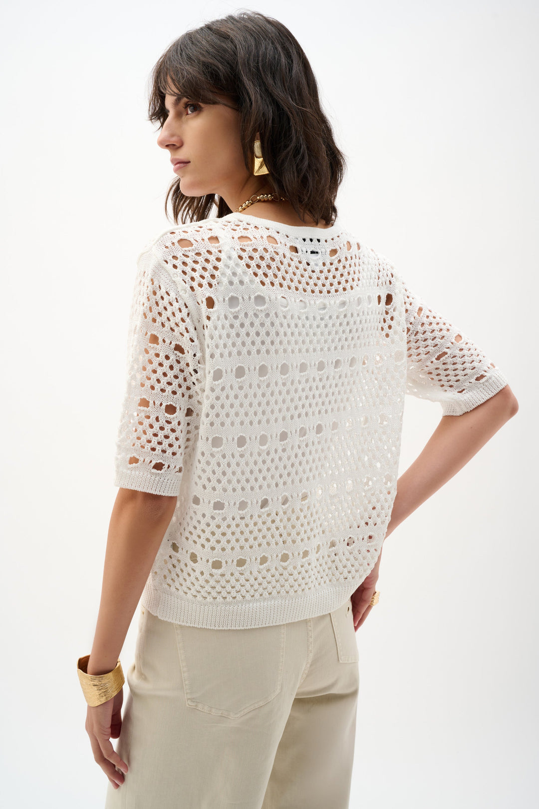 White open-knit sweater with cutout pattern worn by model, back view showing textured stitch detail