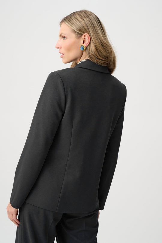 Black blazer back view with curved seam and smooth long sleeves.