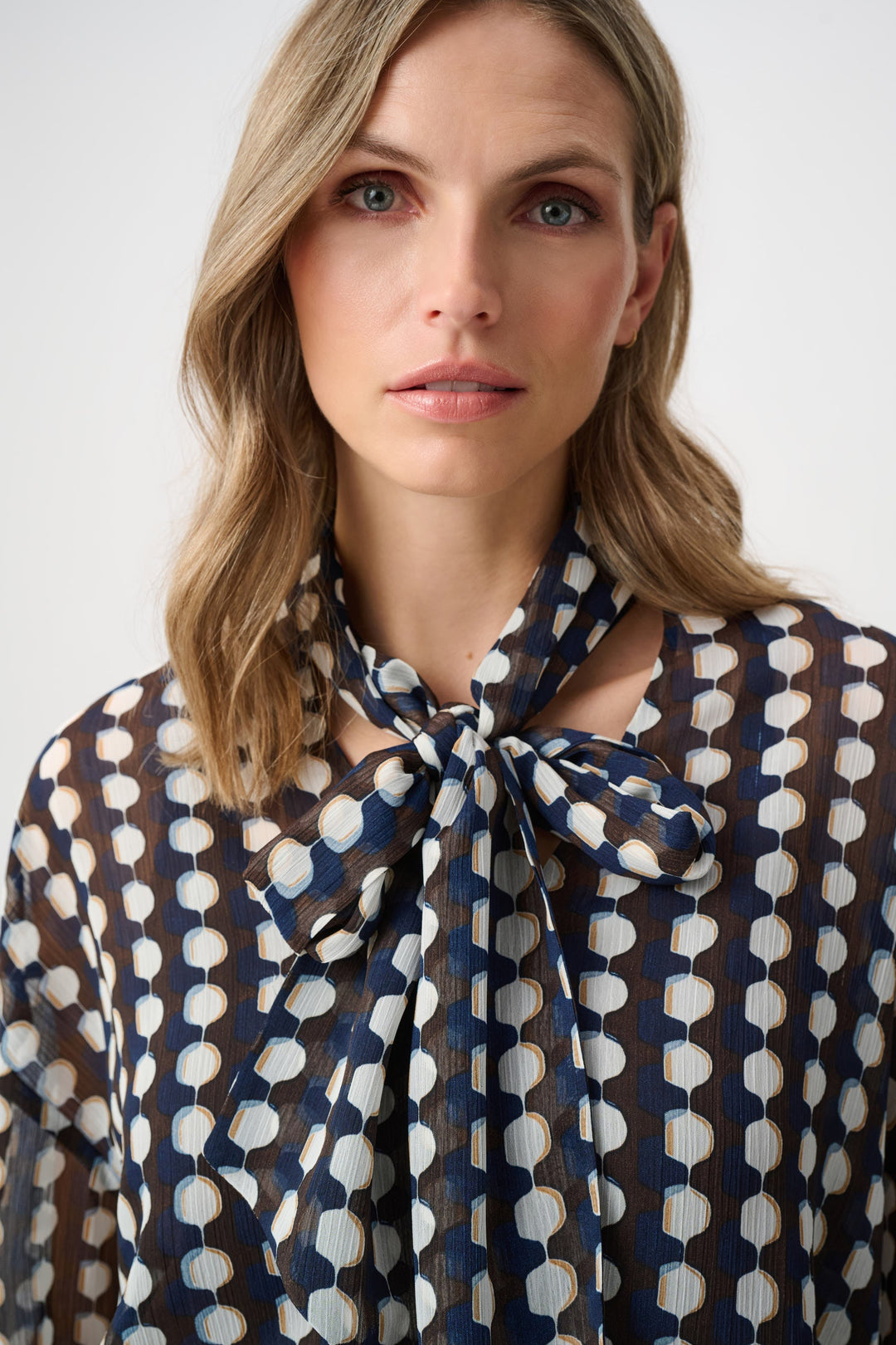 Close-up of tie-neck chiffon blouse with blue and brown geometric print bow