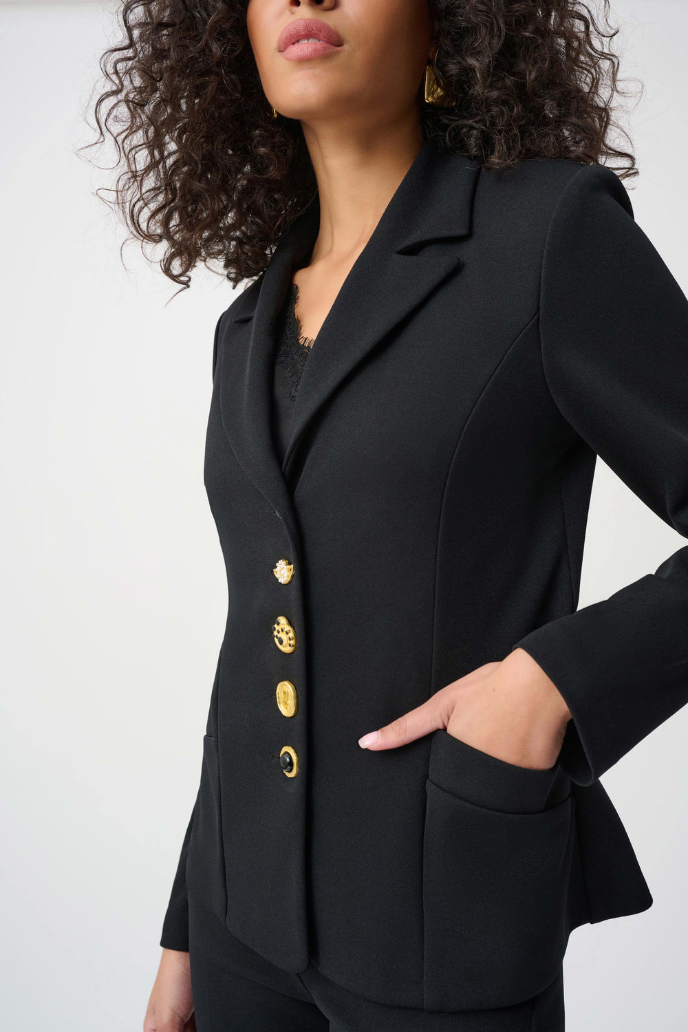 Black blazer detail with gold statement buttons and V-neck lapel, flap pocket visible