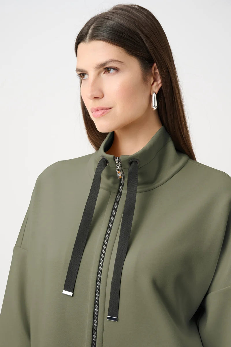 Avocado green funnel-neck jacket detail with black drawstring ties and silver zipper.
