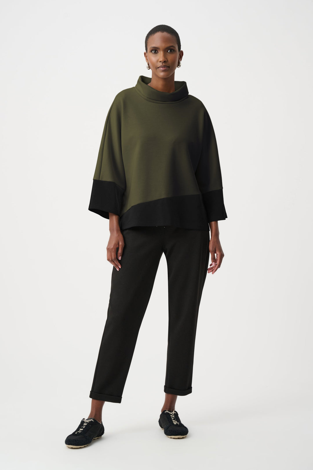 Color block trapeze top with cowl neck in olive green and black worn with black pants