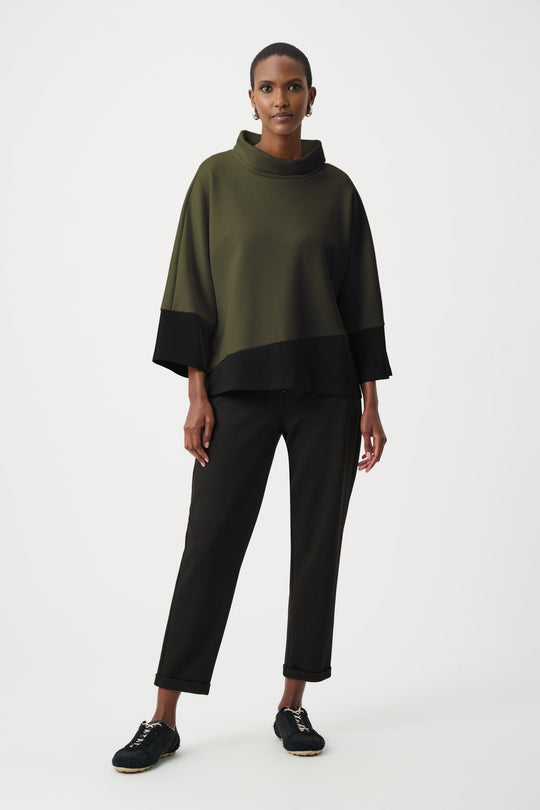 Color block trapeze top with cowl neck in olive green and black worn with black pants