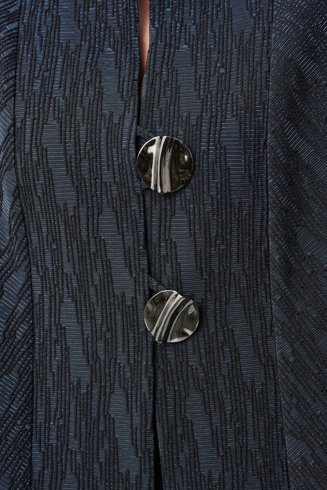 Navy textured jacquard jacket detail showing two metallic buttons and fabric pattern