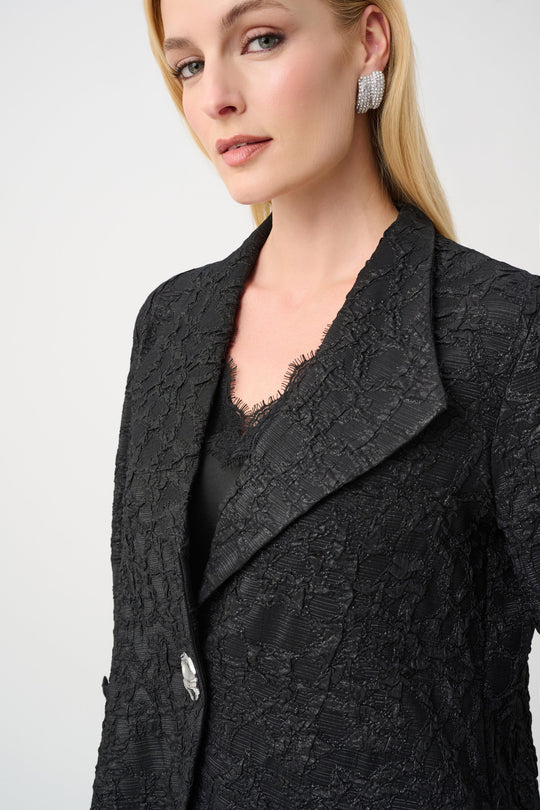 Black textured jacquard blazer with lapels and button closure on model, front angled view