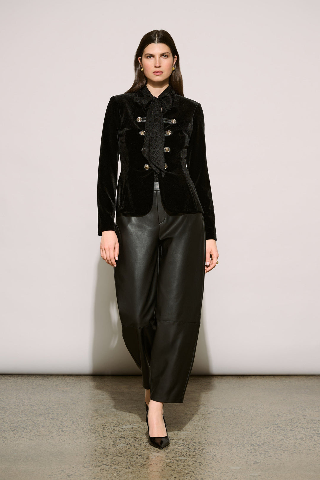 Model wearing black leatherette barrel leg pants with velvet military blazer