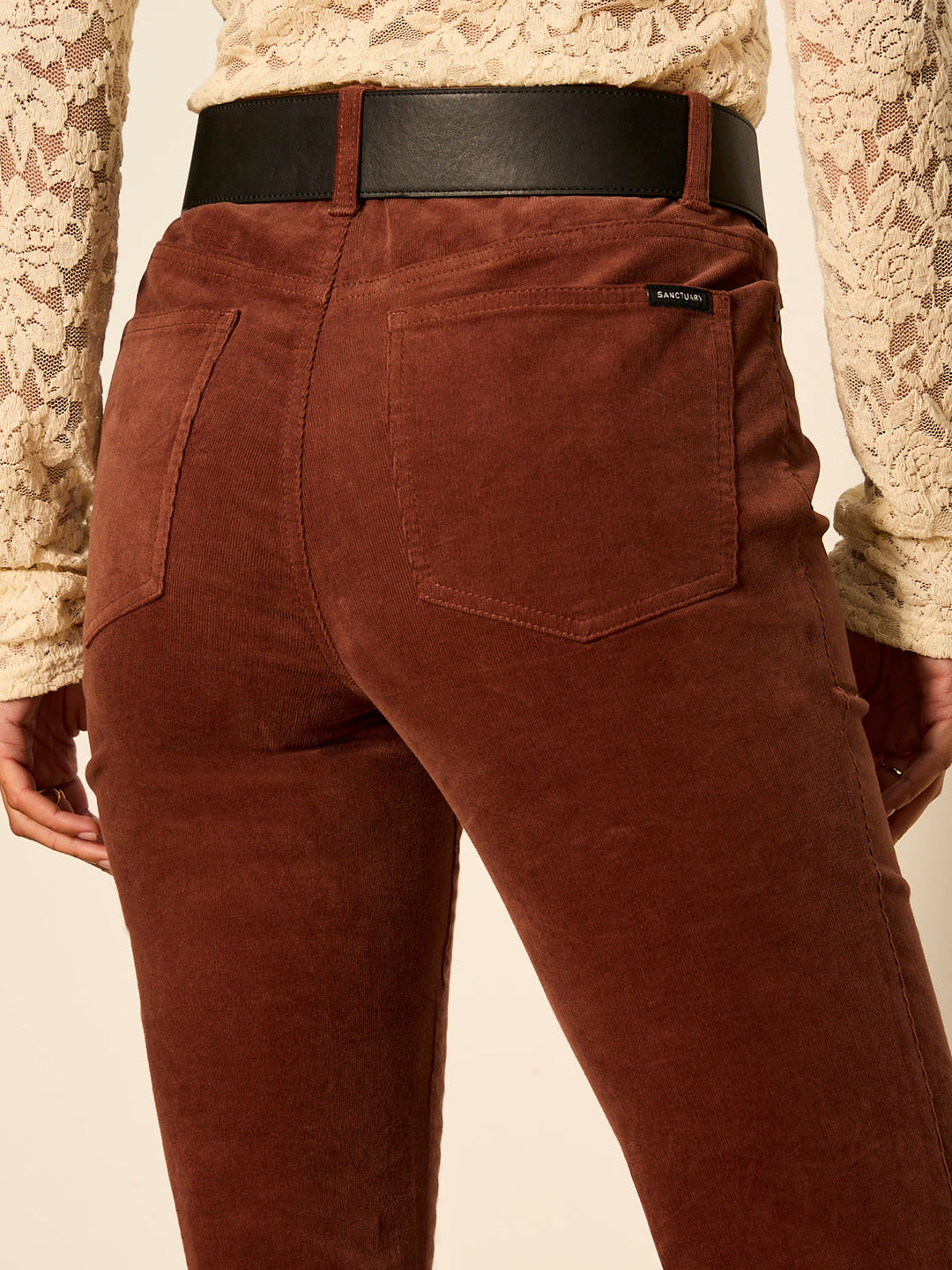Close-up of burnt cocoa bootcut jeans: front pocket and waistband with belt