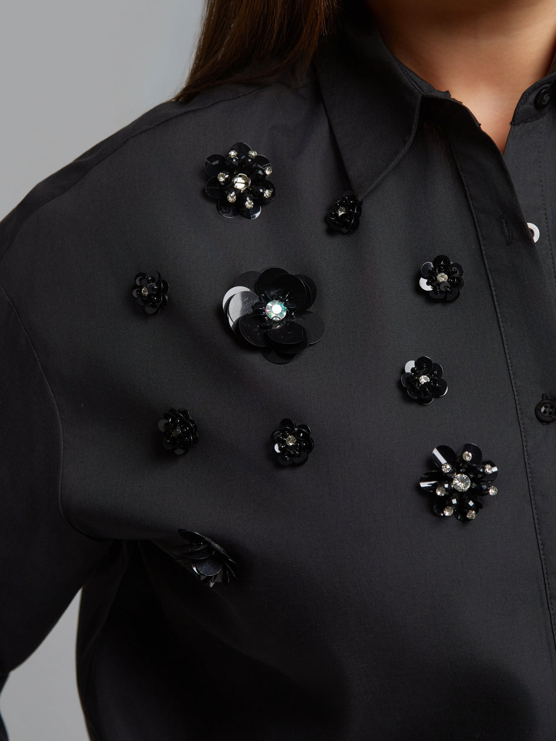 Black shirt close-up with black and iridescent jet bead flower accents on chest