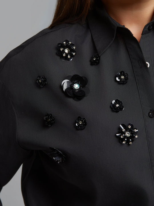 Black shirt close-up with black and iridescent jet bead flower accents on chest