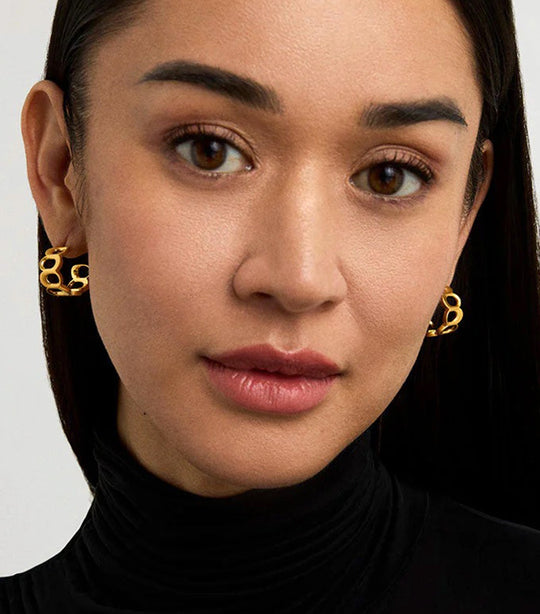 Gold chain-link huggie hoop earrings worn by a model, close-up lifestyle view