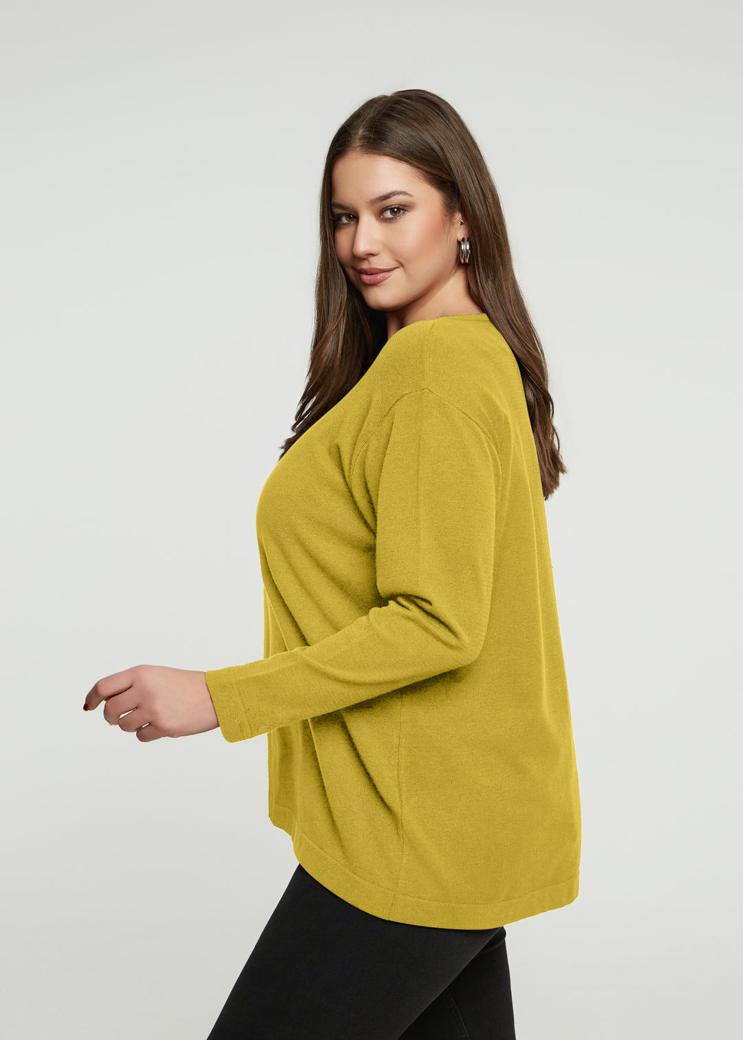 Woman wearing a mustard yellow sweater on a white background