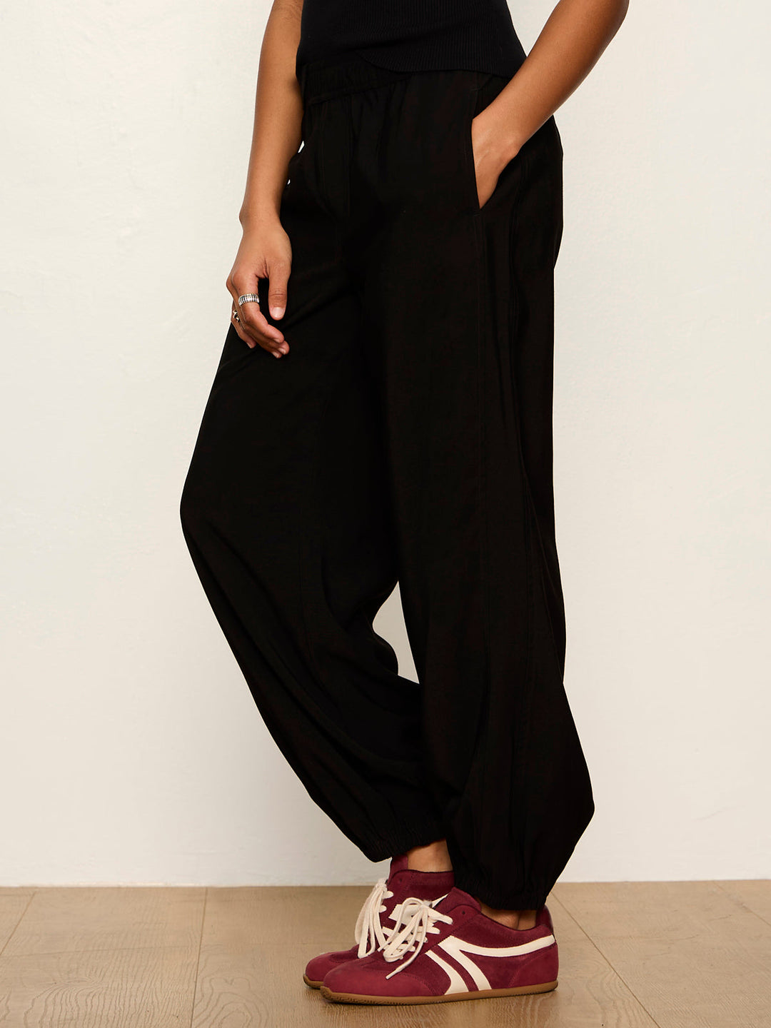 Black balloon-style harem pants with elastic waistband and tapered ankles, side view on model