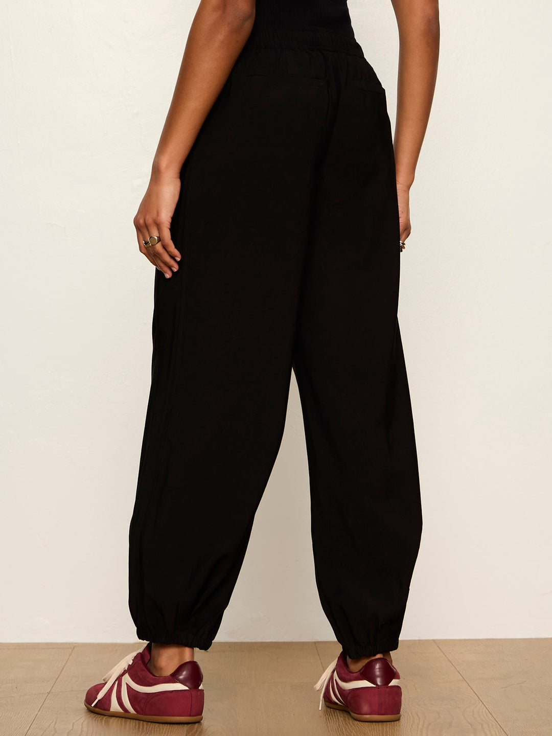 Black balloon jogger pants with elastic waistband and cuffed ankles, rear view on model