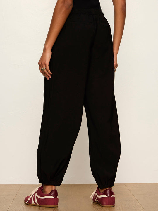 Black balloon jogger pants with elastic waistband and cuffed ankles, rear view on model