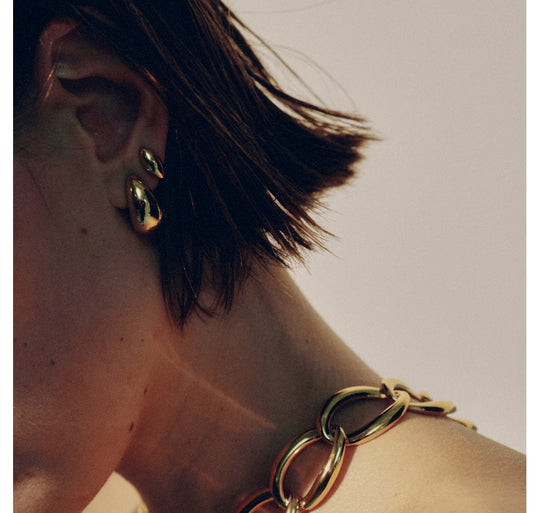 Small gold hoop earrings worn on model with short brown hair, side profile view