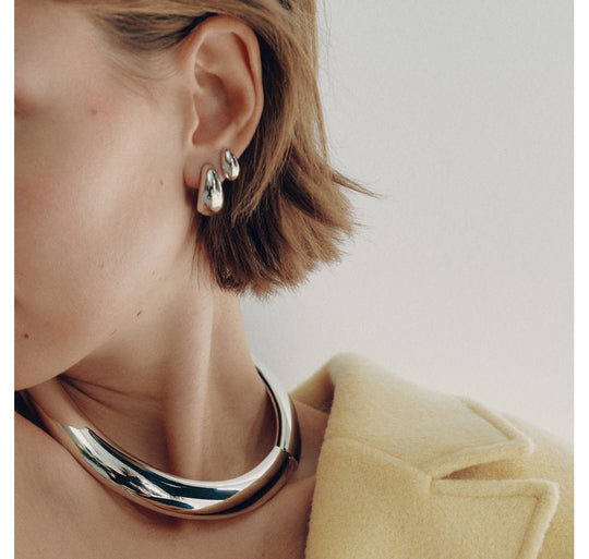 Small metallic hoop earrings worn on model with matching chunky collar necklace