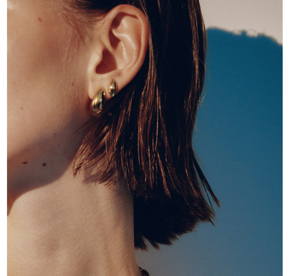 Small gold hoop earrings worn on ear, chunky twisted design