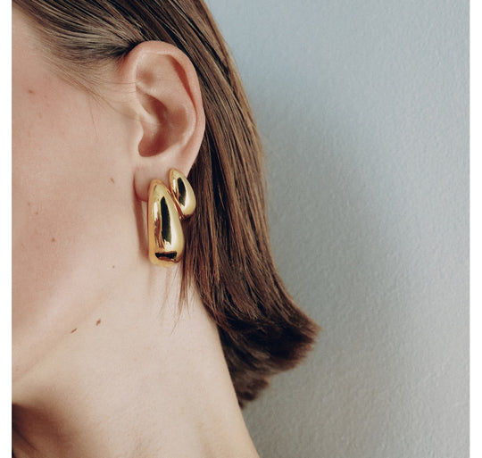 Small gold hoop earrings worn on model, showing curved chunky design