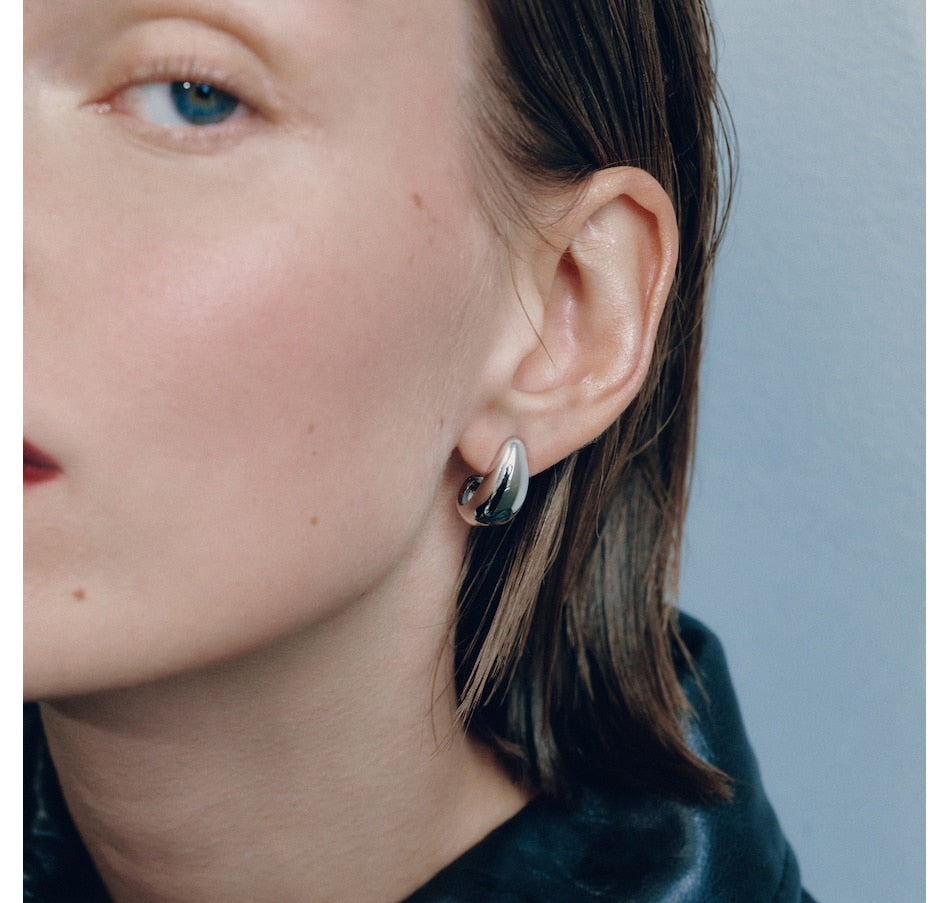 Small silver hoop earring worn on ear, side profile view showing smooth curved design