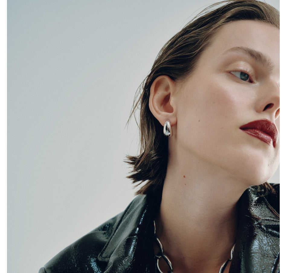 Small metallic hoop earrings worn by model with dark hair and red lipstick