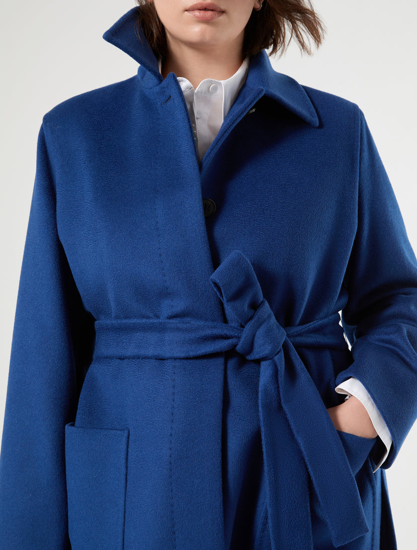 Royal blue wool coat with self-tie belt, patch pocket, covered button placket, and shirt collar, front detail view