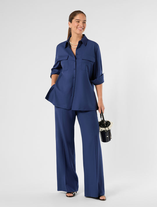 Oversized navy blue button-up shirt jacket with chest pockets and rolled sleeves, front view on model