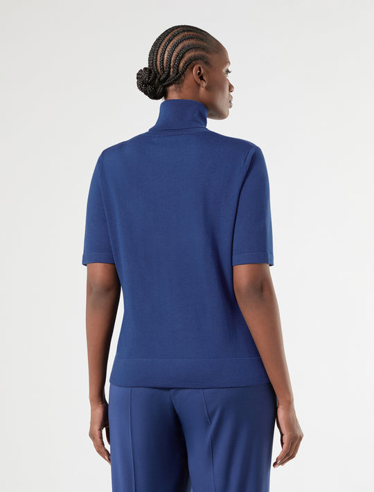 Short sleeve turtleneck knit top in blue, back view on model with braided updo