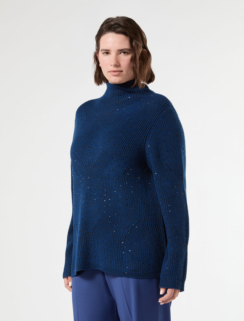 Ribbed knit mock neck sweater with scattered metallic studs in deep blue, three-quarter view on model