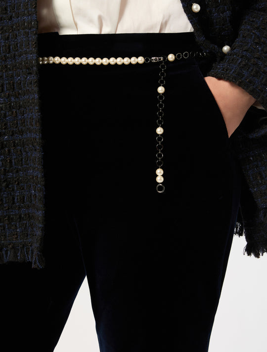 Pearl and chain belt worn at the waist over dark velvet trousers, with dangling embellished drop