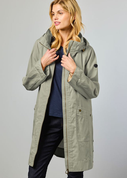 Woman wearing a long green coat against a plain background