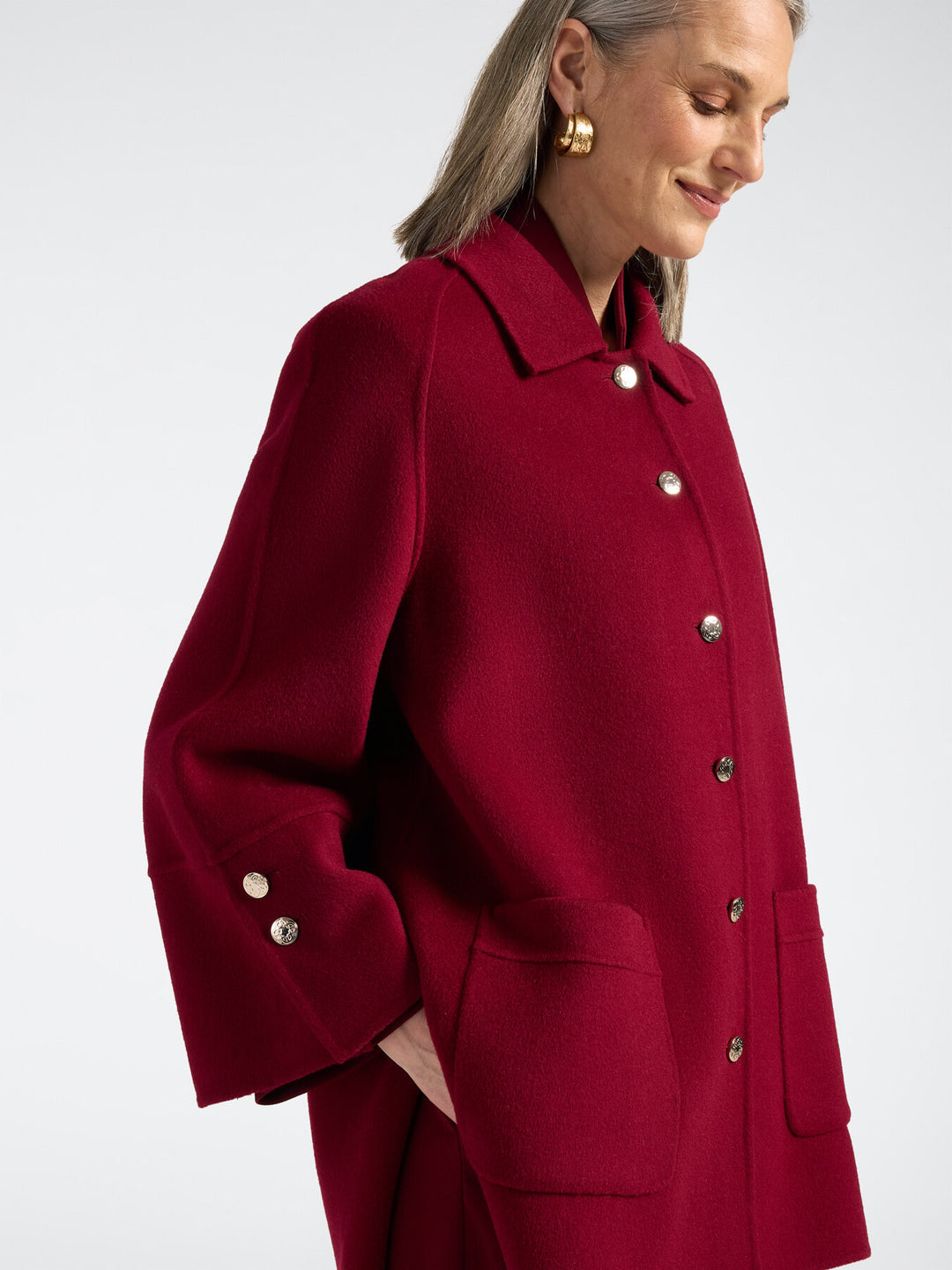 Red double-face coat close-up with buttoned cuff and deep side pocket