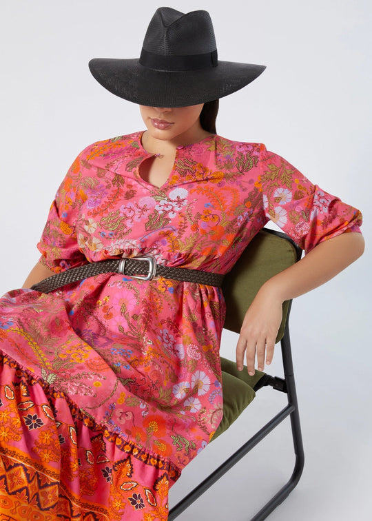 front view of Marina Rinaldi Stecca Cotton Print Tiered Long Dress styled with belt and sun hat on plus model in Fuchsia Print